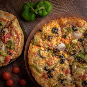 pizza with green bell pepper and cheese on brown wooden table